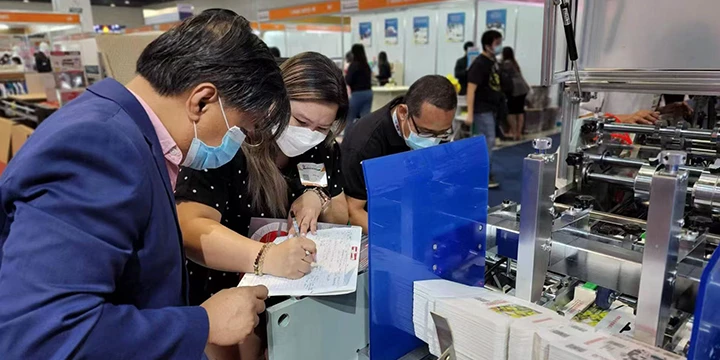 Hongshuo team discussing paper machinery with partners at an exhibition